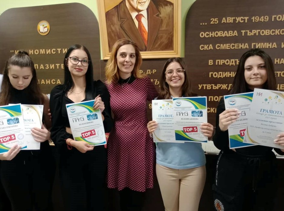 Наградени ученици с грамоти пред стената с историята на гимназията